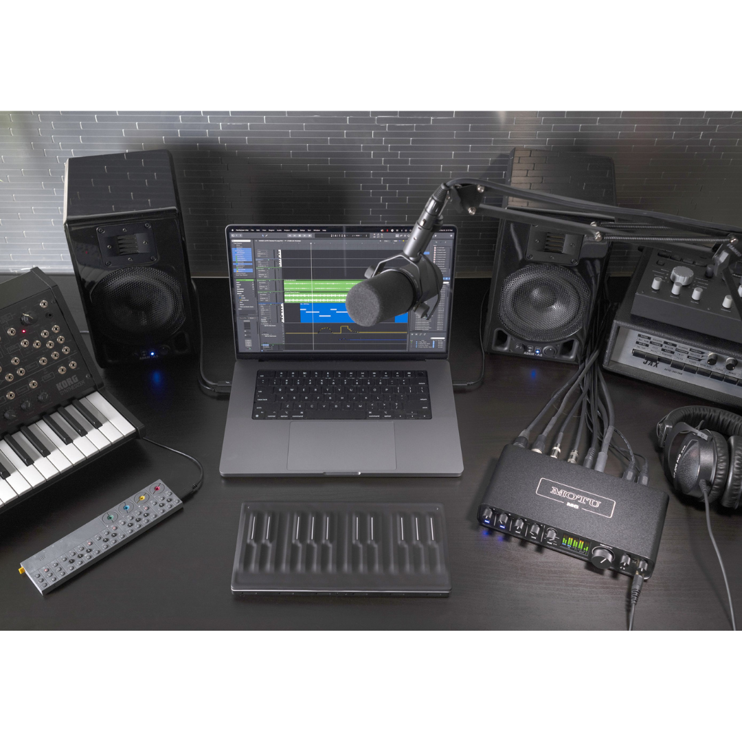 MOTU M6 Audio Interface on dark studio desk with studio monitors, condenser mic, MIDI keyboard and DAW laptop
