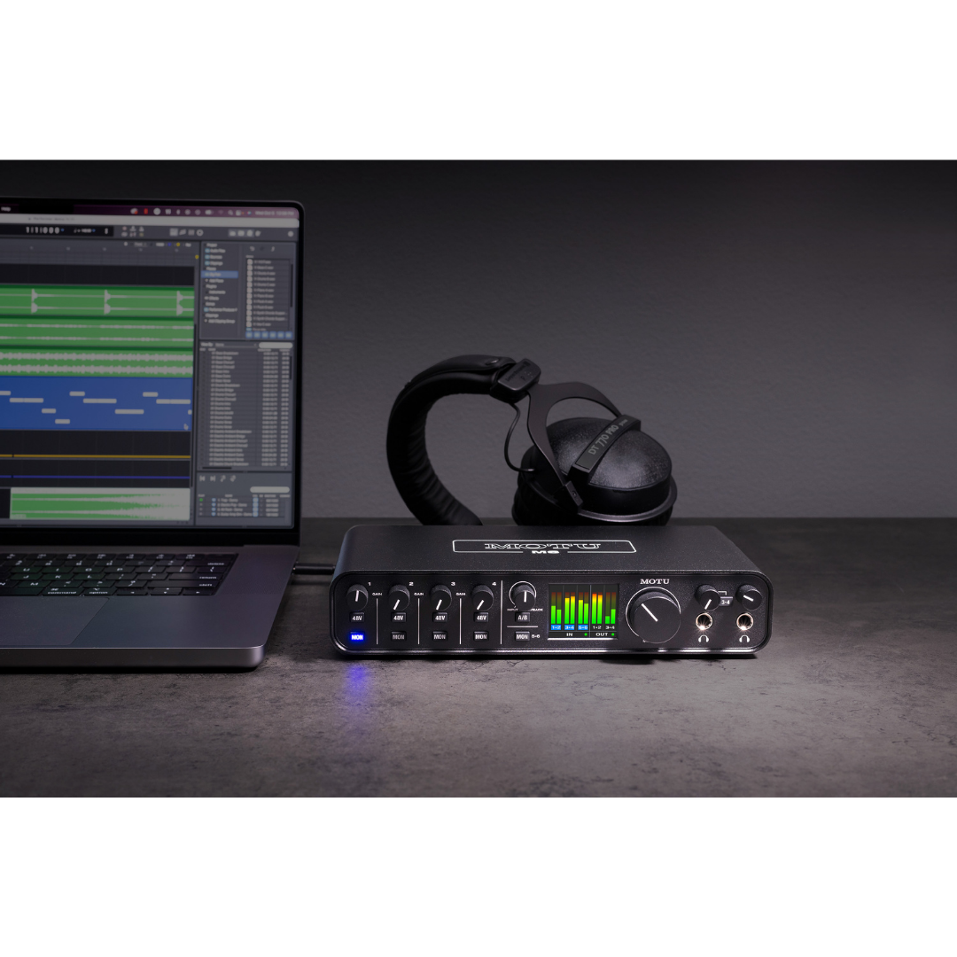 MOTU M6 Audio Interface front panel with LED meters, headphones and DAW laptop for studio recording