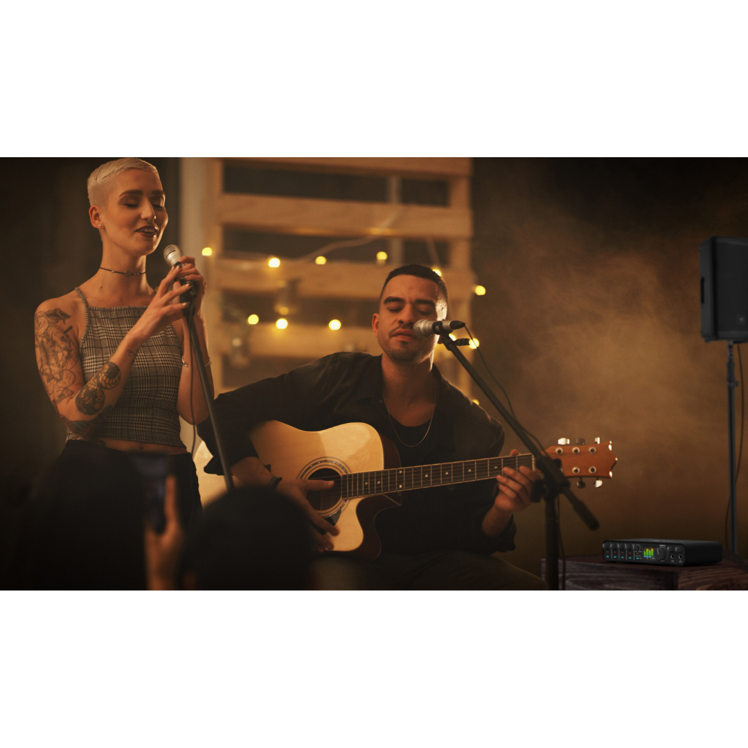 MOTU M6 Audio Interface used in live performance setup with vocalist, acoustic guitarist and stage microphones